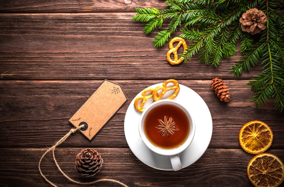 A cozy rustic setting with a teacup, cinnamon, pretzels, and pine decorations on a wooden table.