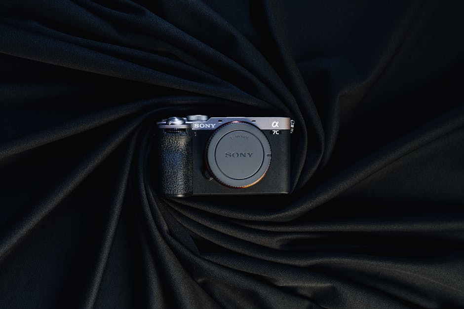 Compact camera elegantly displayed on draped black fabric, emphasizing modern design and sophistication.