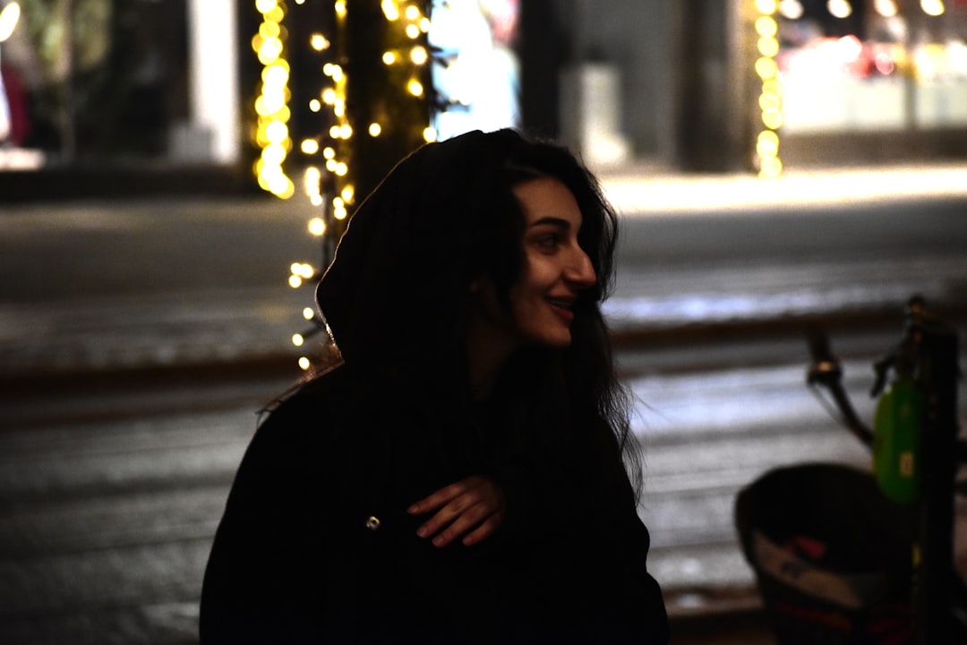 a woman standing in front of a street with christmas lights