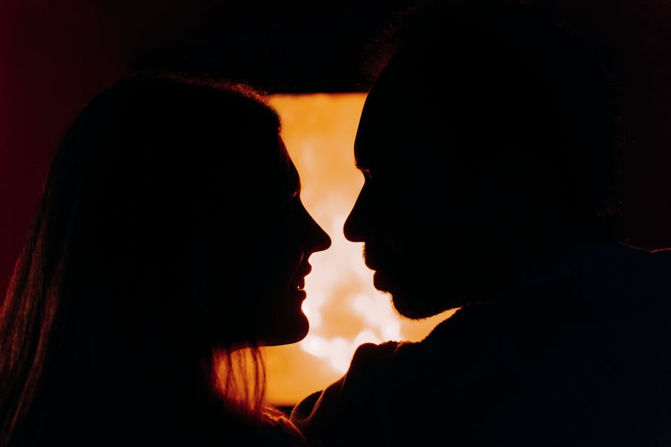 Silhouette of a couple sharing a romantic moment by a warm fireplace.