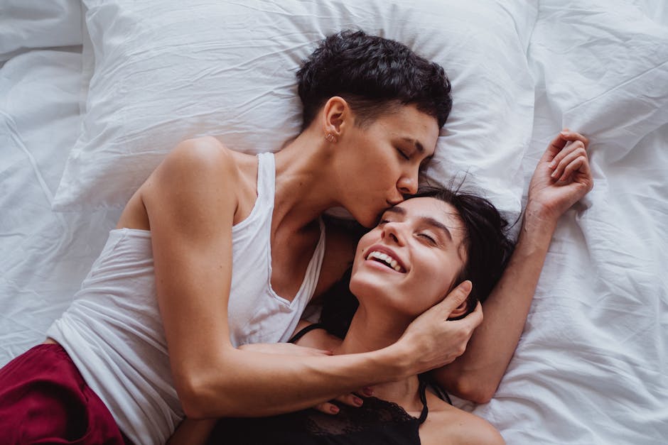 Two women embracing affectionately in bed, illustrating love and intimacy.
