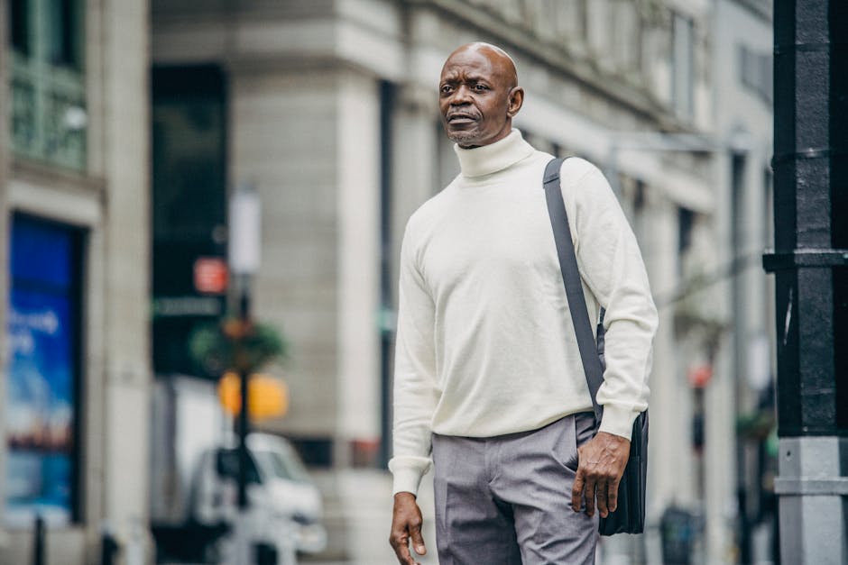 Low angle of confident African American businessman in trendy outfit standing on street in downtown