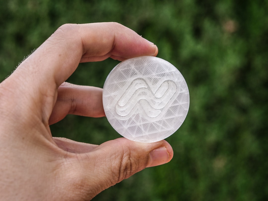 Hand holding a round object with a white wavy pattern.