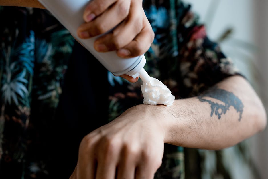 A person applying whipped cream onto a tattooed arm, close-up view.