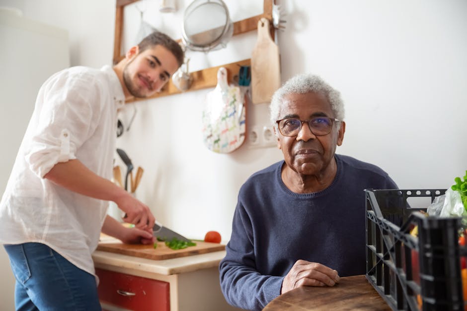 A young adult helping a senior in the kitchen, highlighting care and support at home.