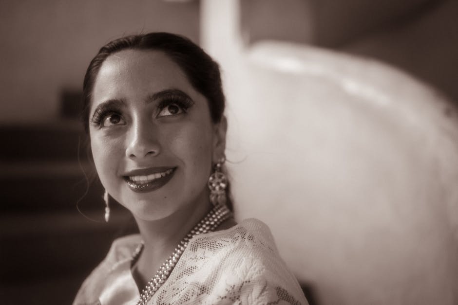 Sepia-toned portrait of a smiling woman wearing jewelry, captured indoors in Huauchinango, Mexico.