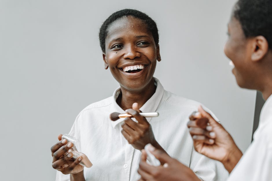 Two women smiling and applying makeup, reflecting friendship and beauty routine in a minimalistic setting.