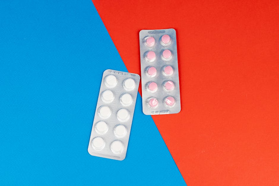 Flat lay of pill blister packs on a red and blue surface, ideal for healthcare themes.
