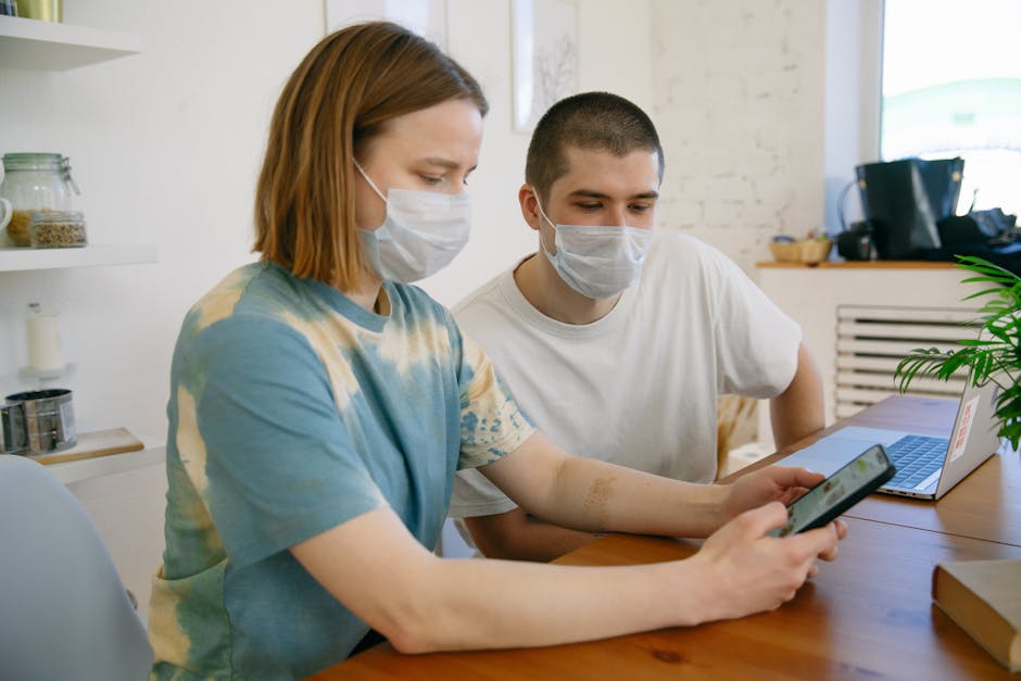 A couple with face masks using a smartphone indoors, embodying the new normal.