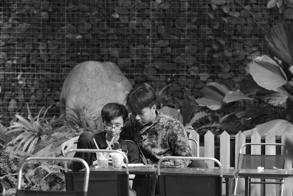 Two young adults focused on work in an outdoor garden cafe.