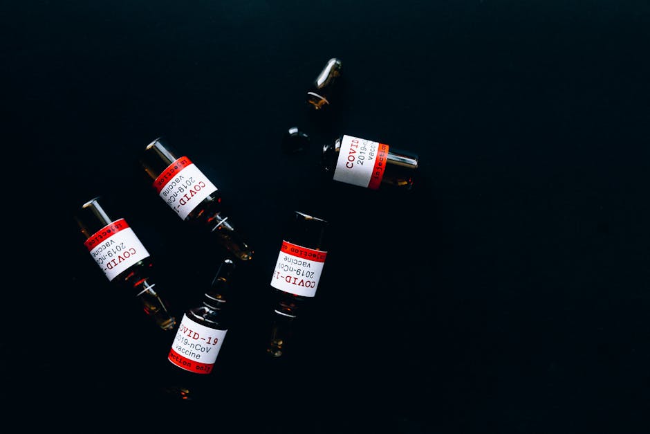 Five COVID-19 vaccine vials against a dark backdrop, symbolizing healthcare and pandemic response.