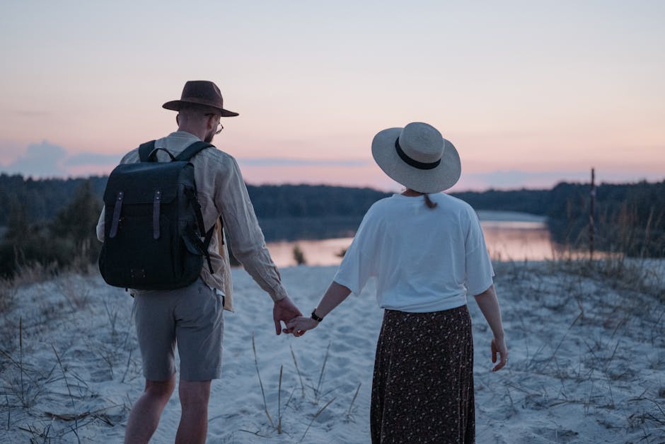 A couple holding hands walking on a sandy beach with sunset views, evoking a sense of love and tranquility.
