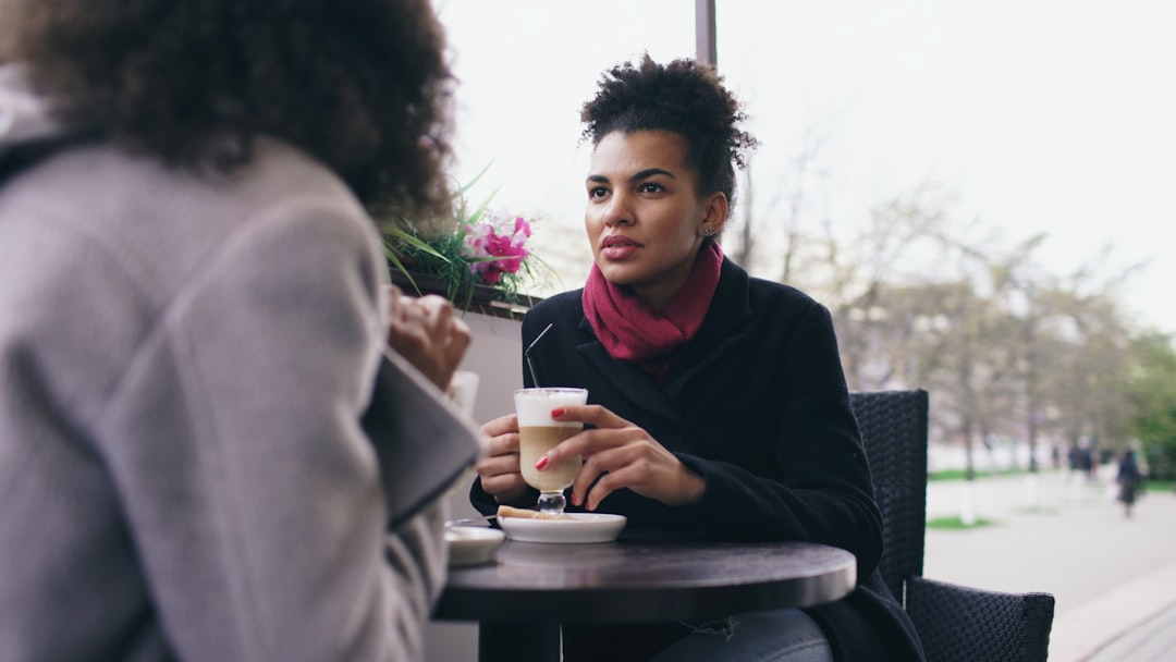 Two women talking at an outdoor cafe table.