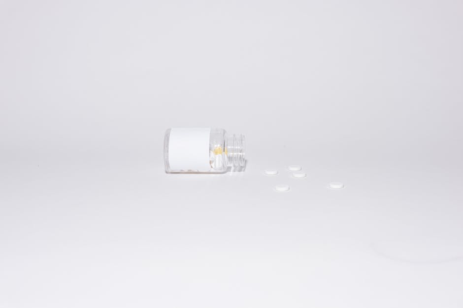 Minimalist photo of white pills and an open bottle on a white background, emphasizing emptiness.